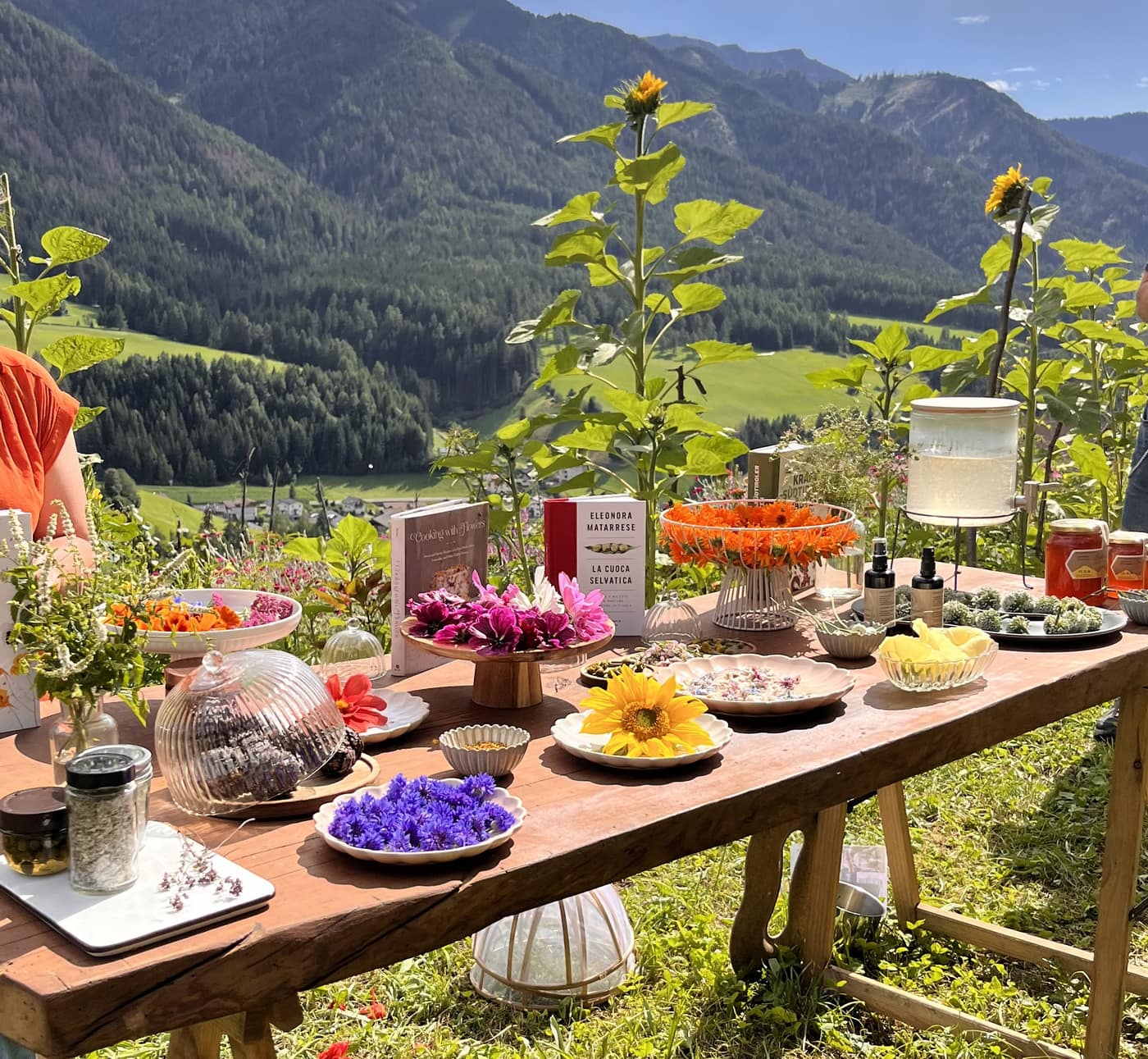 Brunch-Tafel mit Sonnenblumen, Schalen voller Blütenblätter und Bergpanorama